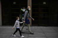 A father with his children wearing face mask to prevent the coronavirus go for a walk at Carlos III promenade, in Pamplona, northern Spain, Sunday, April 27, 2020. On Sunday, children under 14 years old will be allowed to take walks with a parent for up to one hour and within one kilometer from home, ending six weeks of compete seclusion. (AP Photo/Alvaro Barrientos)