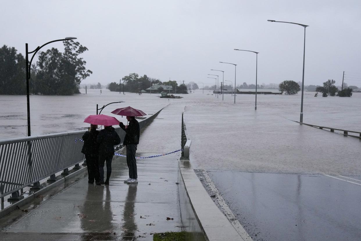 People look at the flooded Windsor Bridge on the outskirts of Sydney, Australia, Monday, July 4, 2022.
