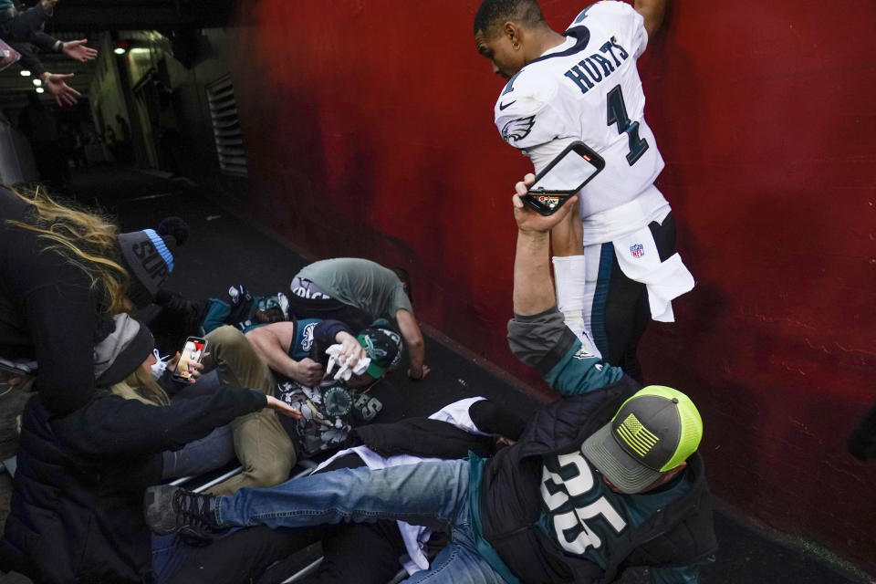 Fans hit the ground infront of Philadelphia Eagles quarterback Jalen Hurts (1) after a railing collapsed following the end of an NFL football game, Sunday, Jan. 2, 2022, in Landover, Md. Philadelphia won 20-16. (AP Photo/Alex Brandon)