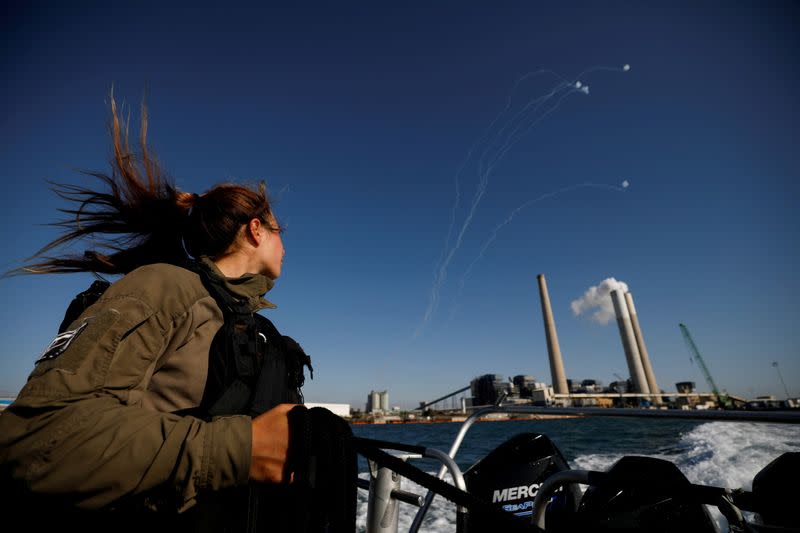 FILE PHOTO: An Israeli soldier looks on as Israel's Iron Dome anti-missile system intercept rockets launched from the Gaza Strip towards Israel, as it seen from a naval boat patrolling the Mediterranean Sea