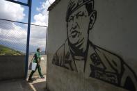 Nurse Genny Zorrilla walks with a cooler containing Sinopharm COVID-19 vaccines past a mural of late president Hugo Chavez, during house to house vaccinations in the popular neighborhood of El Valle in Caracas, Venezuela, Monday, Sept. 27, 2021. According to the Pan American Health Organization Venezuela one of the least vaccinated countries in the continent, is seeing a growing uptick in caseloads, unlike other countries in the region where cases are dropping. (AP Photo/Ariana Cubillos)