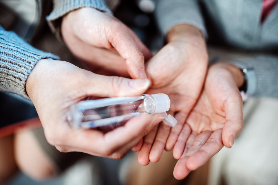 Mom squeezing hand sanitizer onto littler daughter’s hands