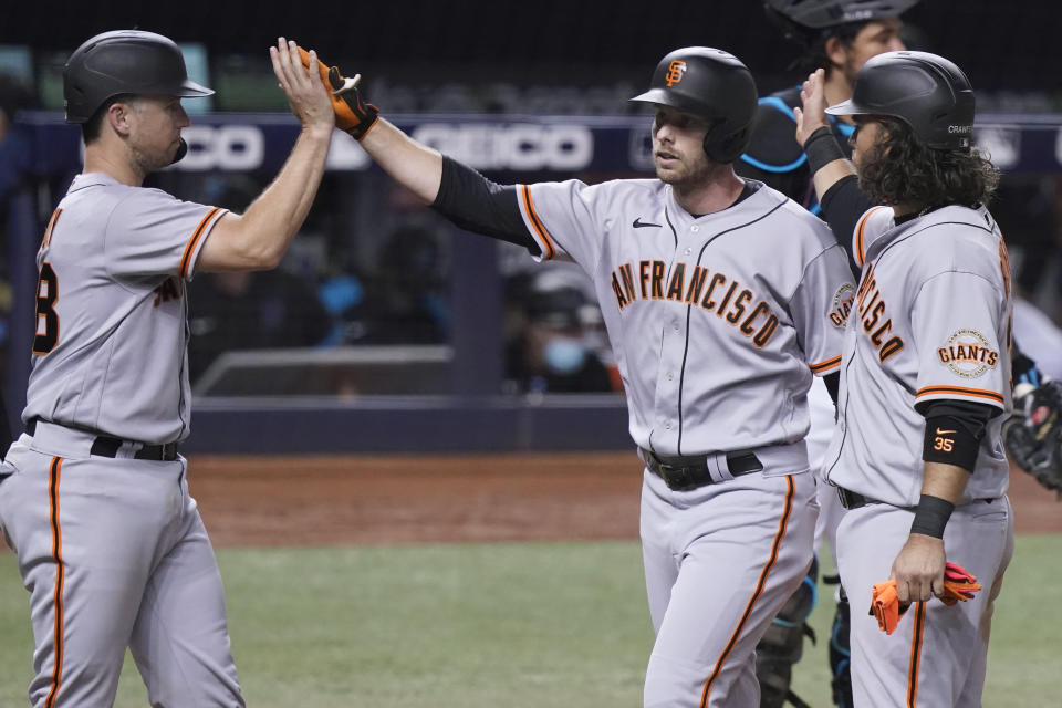 San Francisco Giants' Austin Slater, center, is congratulated by Buster Posey, left, and Brandon Crawford after Slater hit a three-run home run during the seventh inning of the team's baseball game against the Miami Marlins, Saturday, April 17, 2021, in Miami. (AP Photo/Marta Lavandier)