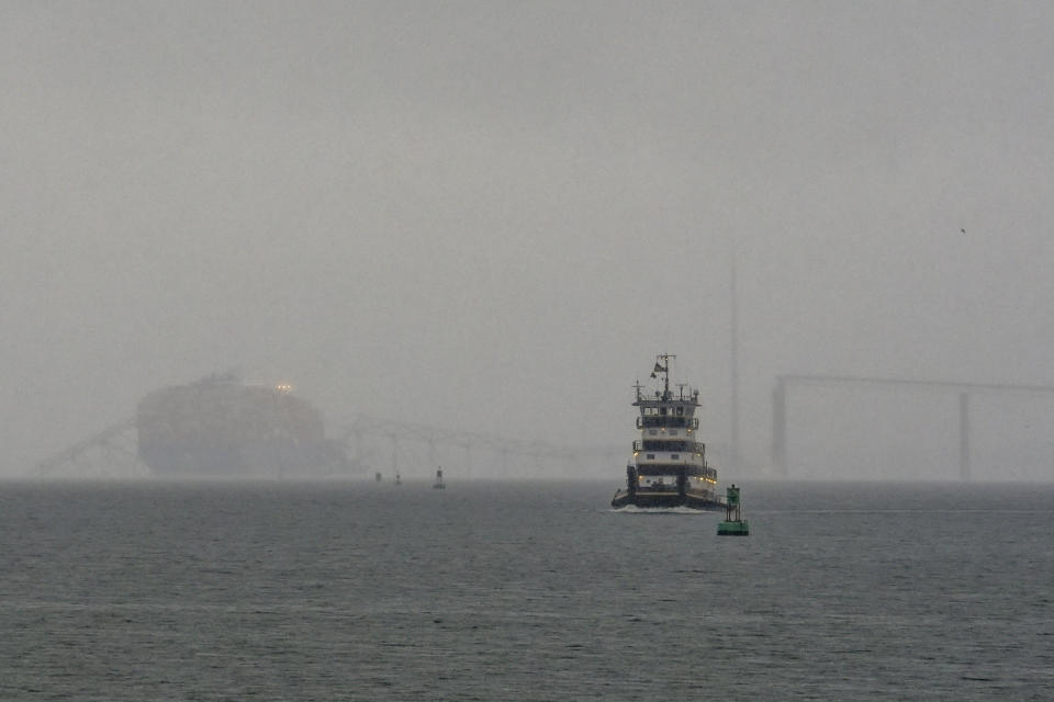 A tugboat moves by a container ship as it rests against the wreckage of the Francis Scott Key Bridge on Wednesday, March 27, 2024, in Baltimore. The ship rammed into the major bridge early Tuesday, causing it to collapse in a matter of seconds and creating a terrifying scene as several vehicles plunged into the chilly river below. (AP Photo/Matt Rourke)