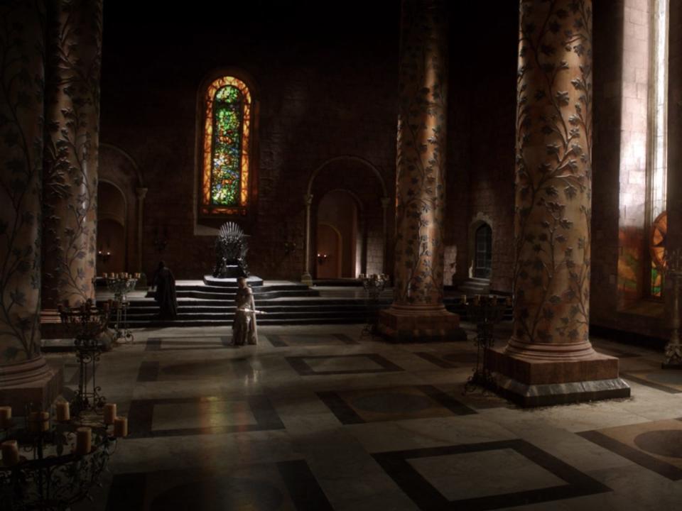 A wide shot of the throne room in "Game of Thrones" season one, with colored stained glass windows.