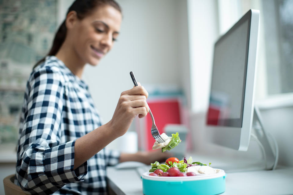 Female working eating lunch at her desk. (Getty Images)