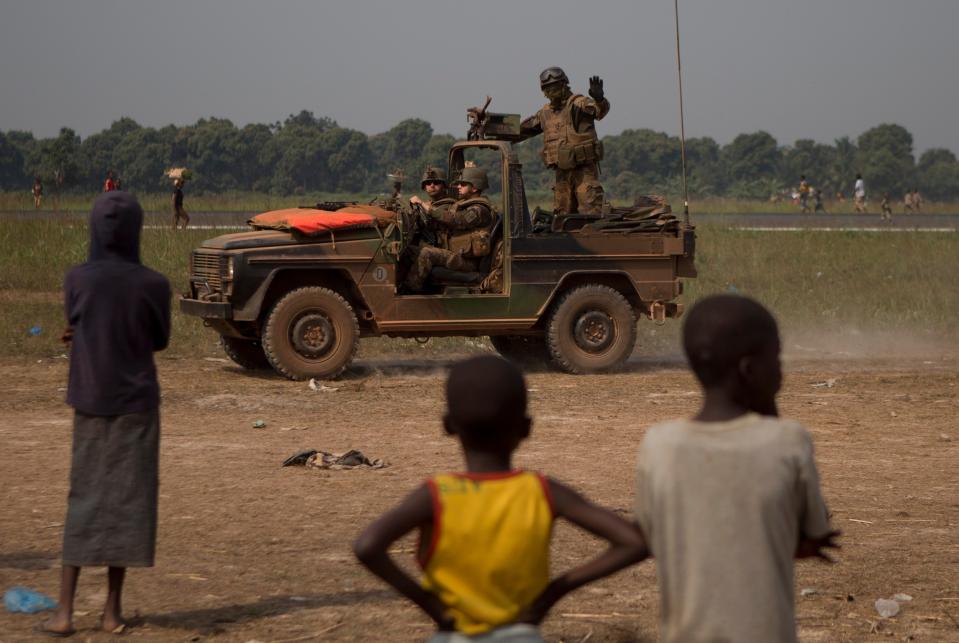 A French soldier waves to children as his jeep patrols between the airstrip and a makeshift camp housing an estimated 100,000 displaced people, at Mpoko Airport, in Bangui, Central African Republic, Thursday, Jan. 9, 2014. Embattled President Michel Djotodia who has come under growing pressure to resign, was in neighboring Chad on Thursday for a summit with regional leaders who want to end the bloodshed that has left more than 1,000 dead and nearly a million people displaced. (AP Photo/Rebecca Blackwell)