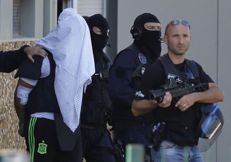 The suspect held over an attack against a gas company site is escorted by police officers during investigations in Saint-Priest, near Lyon, France, June 28, 2015. REUTERS/Emmanuel Foudrot