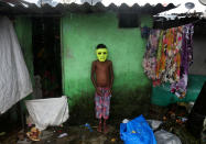 <p>Ein mit einer Maske verkleideter Junge in Mumbai sucht unter einem Dachvorsprung Schutz vor dem Regen. (Bild: REUTERS/Shailesh Andrade) </p>