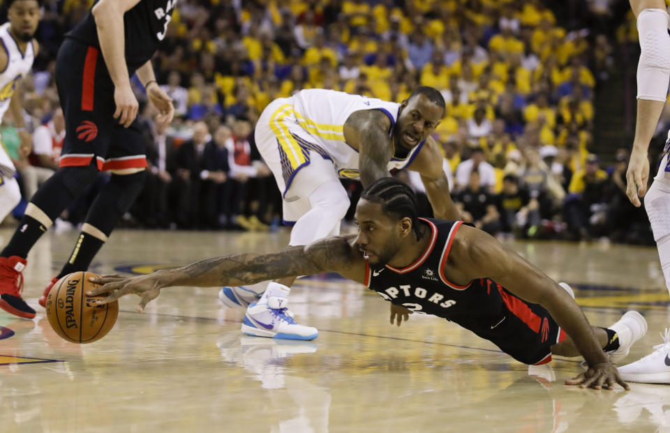 Toronto Raptors forward Kawhi Leonard, foreground, reaches for the ball in front of Golden State Warriors forward Andre Iguodala during the first half of Game 3 of basketball's NBA Finals in Oakland, Calif., Wednesday, June 5, 2019. (AP Photo/Ben Margot)