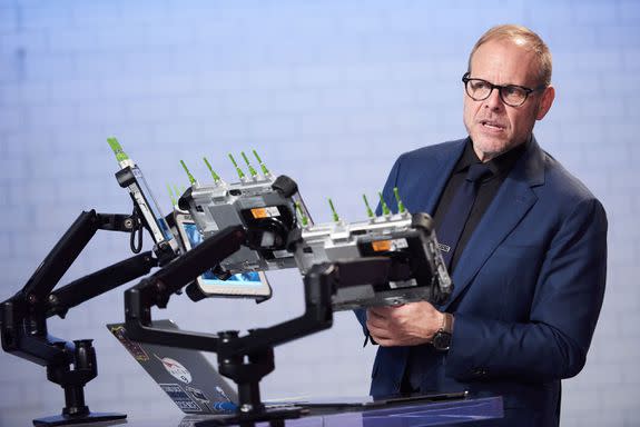 Host Alton Brown watching the chefs prepare their dishes for the Chairman Challenge, as seen on Iron Chef Gauntlet, Season 1.