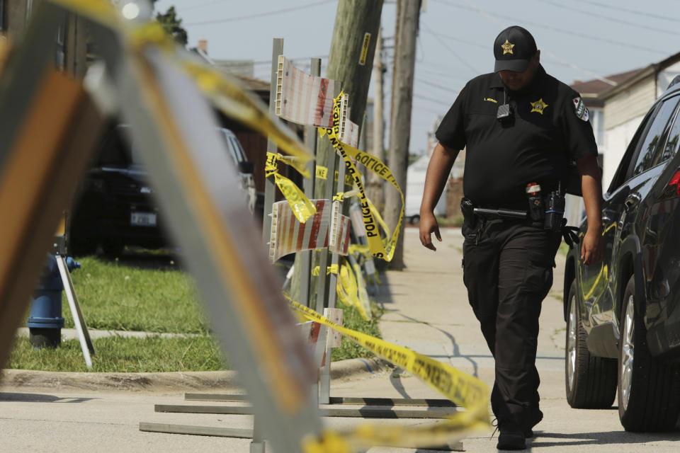 A police officer walks near the barricade along Center Avenue in Lyons, Ill., where authorities believe they've uncovered bodies in the backyard on Saturday, Aug. 28, 2021. Authorities are planning to excavate the suburban Chicago backyard this weekend after two adult brothers found living in what police called a “hoarder home” said they had buried the bodies of their mother and sister there. (Stacey Wescott /Chicago Tribune via AP)