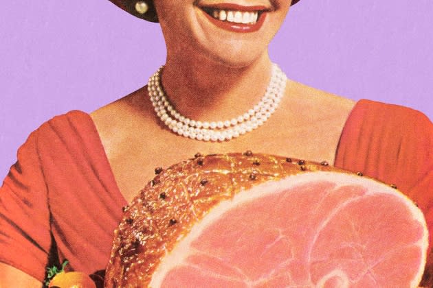 evie-magazine.jpg 1950's housewife holding a ham dinner, smiling - Credit: Getty Images