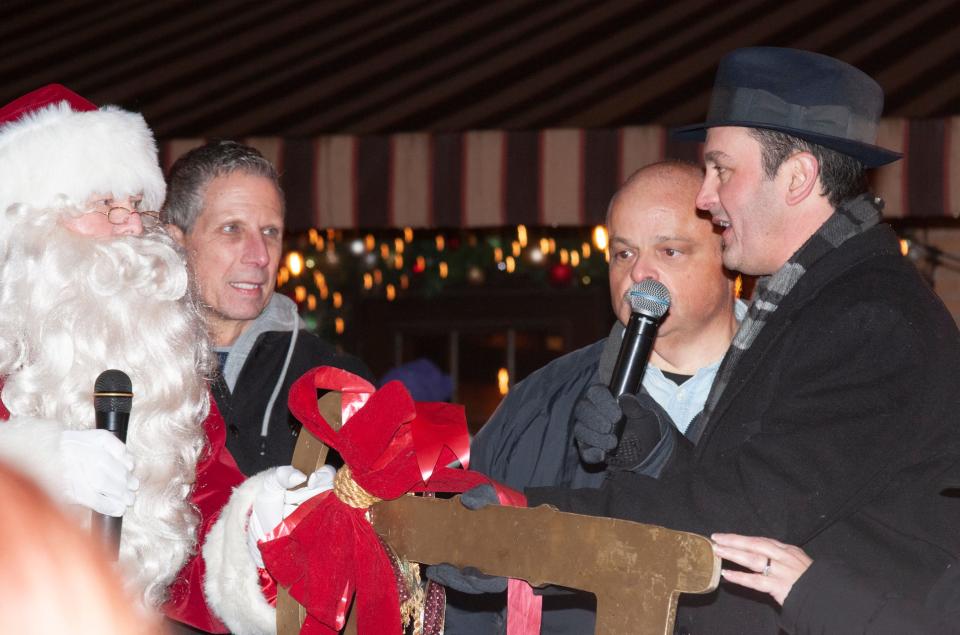 Brighton's newly appointed Mayor Kristoffer Tobbe, right, offers the key to the city to Santa Claus with former WHMI air personalities Mike Marino, left, and Jon King serving as emcees at Brighton's Holiday Glow Saturday, Nov. 20, 2021.