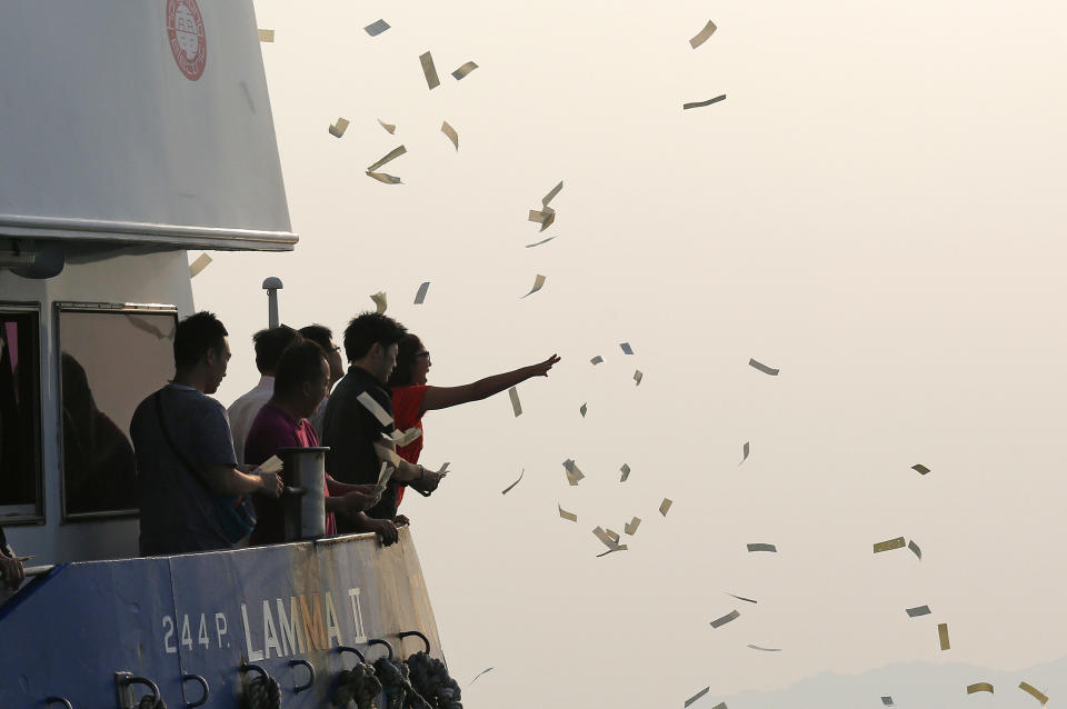 Relatives of the victims throw fake money Tuesday, Oct. 2, 2012 to pay tribute to the ill-fated people aboard a boat that sank Monday night near Lamma Island, off the southwestern coast of Hong Kong Island. The boat packed with revelers on a long holiday weekend collided with a ferry and sank off Hong Kong, killing at least 36 people and injuring dozens, authorities said. (AP Photo/Vincent Yu)