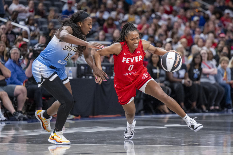 Indiana Fever guard Kelsey Mitchell (0) makes a move toward the basket while being defended by Chicago Sky forward Michaela Onyenwere (12) during a WNBA basketball game Saturday, June 1, 2024, in Indianapolis. (AP Photo/Doug McSchooler)