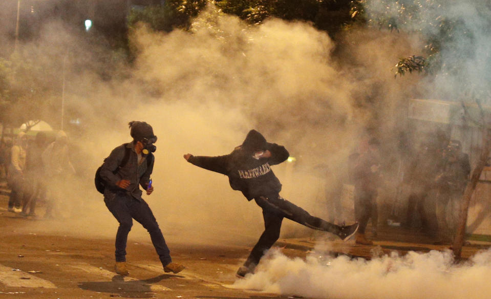 Protesters stand amid tear gas fired by police during a protest against the reelection of President Evo Morales outside the top electoral court during the wait for final results from last weekend's presidential election in La Paz, Bolivia, Wednesday, Oct. 23, 2019. Morales said Wednesday his opponents are trying to stage a coup against him as protests grow over a disputed election he claims he won outright, while a nearly finished vote count had him teetering on the threshold between getting the win or having to go to a runoff. (AP Photo/Juan Karita)