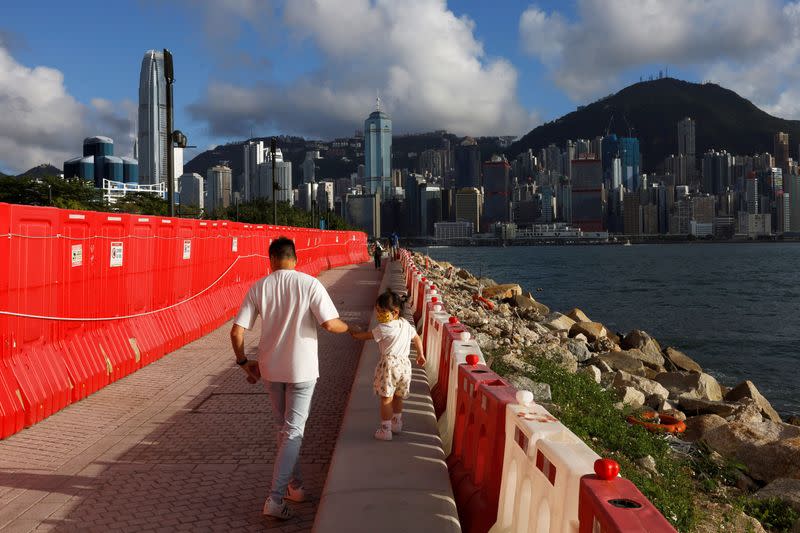 People walk by the Victoria Harbour at West Kowloon Cultural District in Hong Kong