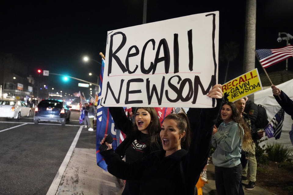 FILE — In this Nov. 21, 2020 file photo demonstrators shout slogans while carrying a sign calling for a recall on Gov. Gavin Newsom during a protest against a stay-at-home order amid the COVID-19 pandemic in Huntington Beach, Calif. Newsom is facing the second recall of a governor in California history. His response to the coronavirus has been a dominating force in the race. (AP Photo/Marcio Jose Sanchez, File)