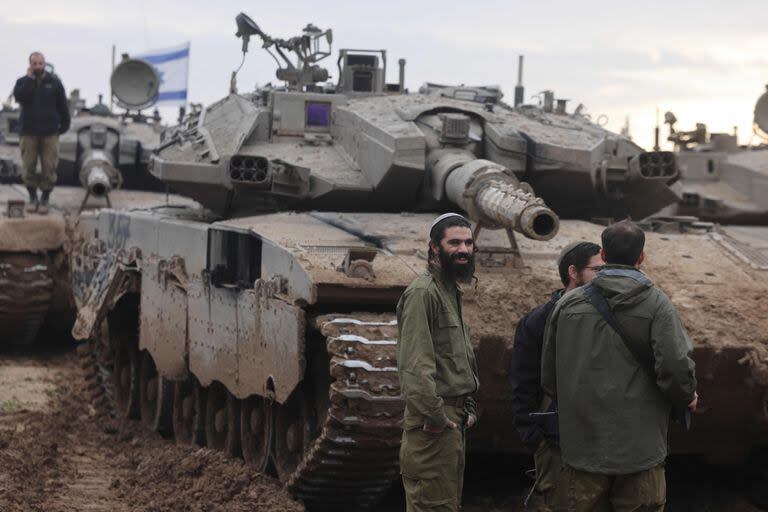 Una foto tomada desde el sur de Israel a lo largo de la frontera con la Franja de Gaza muestra soldados israelíes frente a tanques en una posición a su regreso de una misión en el territorio palestino el 28 de enero
 (Menahem KAHANA / AFP)