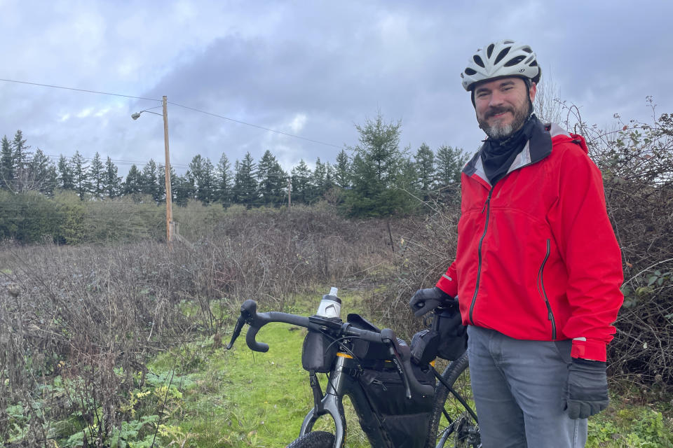 Adam Pirkle stands with his bicycle on the edge of a densely thicketed area in the Cedar Hills area of southwest Portland, Ore., Sunday, Jan. 7, 2024. Pirkle said he rode 14 miles looking for the wreckage of the fuselage that detached from a Boeing 737 Max 9 shortly after the takeoff of an Alaska Airlines flight on Friday, Jan. 5. The National Transportation Safety Board estimated it may have fallen in the area. (AP Photo/Claire Rush)