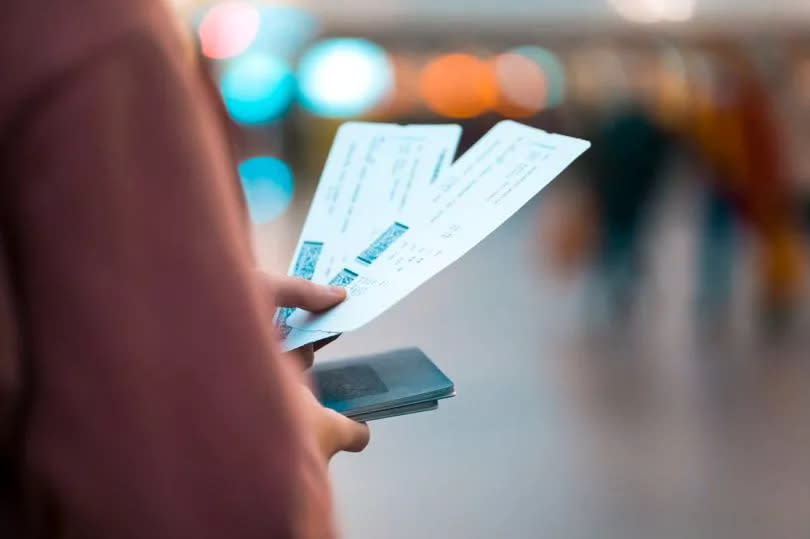 A young girl goes on a trip, holding airline tickets in her hands and going to check-in to board a plane, close-up of a boarding pass on a blurred background.