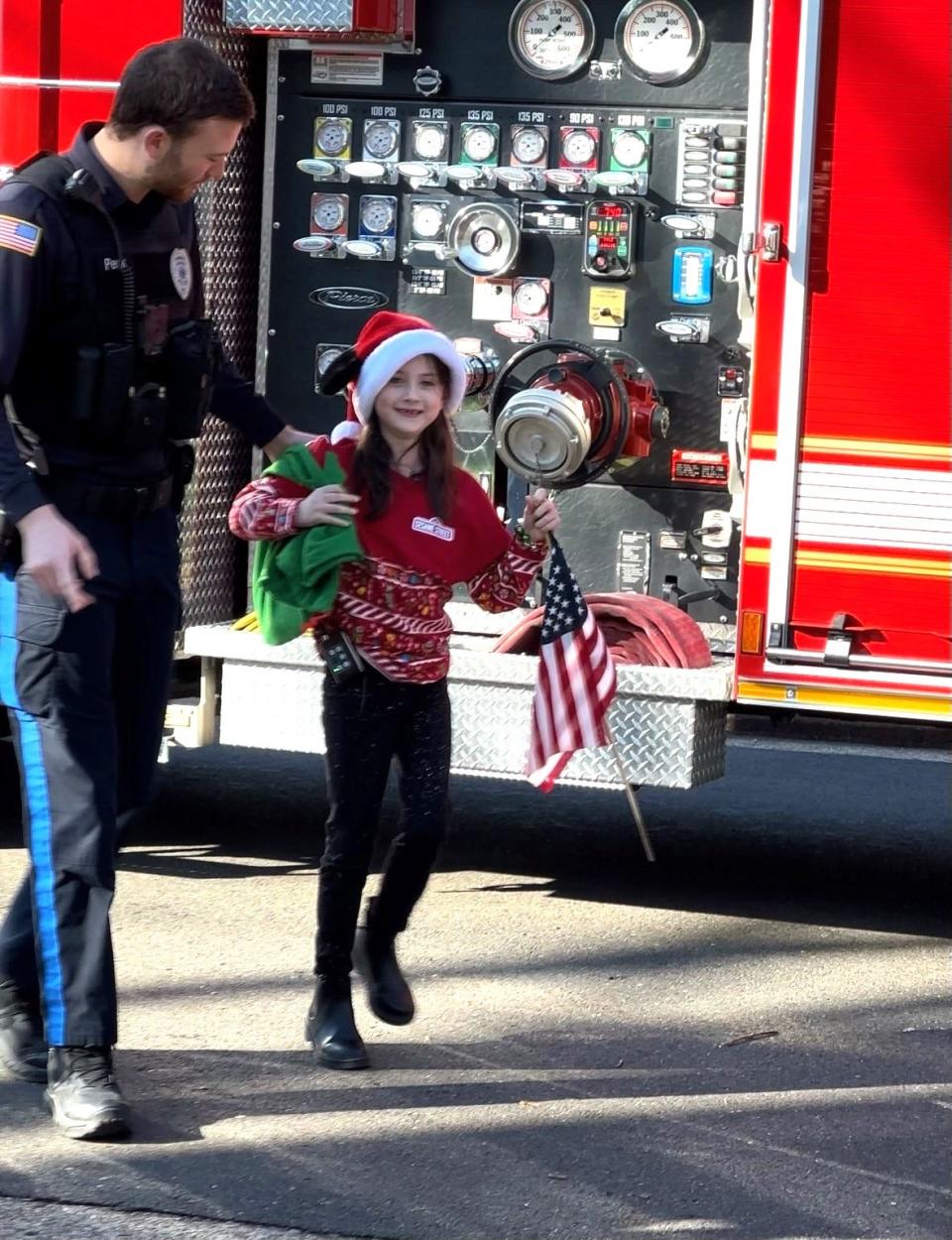 Lalya Leuthy Beck, 7, jumps down from a Newtown Fire Association truck to meet her father, Penndel Police Officer Sean Peck, as they prepare to deliver 100 birthday cards from Layla and her first-grade class at St. Andrew School in Newtown to Joseph Gagliardi, a veteran celebrating his 100th birthday Friday.