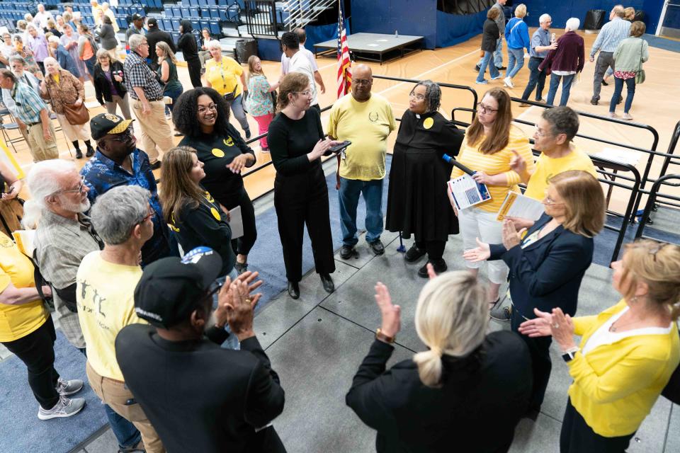 Board members of Topeka JUMP celebrate their success at Monday's Nehemiah Action event at Lee Arena under the direction of lead organizer Sarah Balzer, middle.