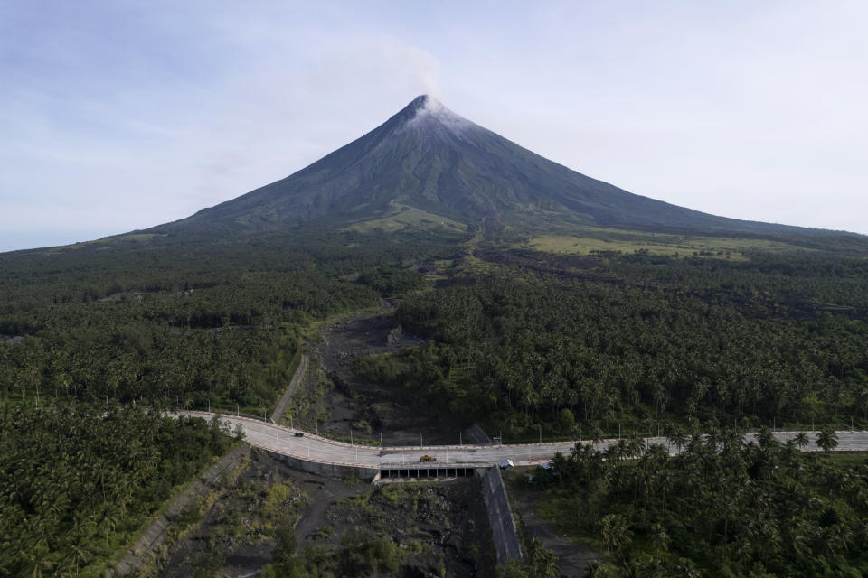 A truck passes by a road near the Mayon volcano as it belches hot emissions down its slope as seen from Daraga town, Albay province, northeastern Philippines, Wednesday, June 14, 2023. The 2,462-meter (8,077-foot) Mayon is a top tourist draw in the Philippines because of its picturesque conical shape but is the most active of 24 known volcanoes in the archipelago. (AP Photo/Aaron Favila)