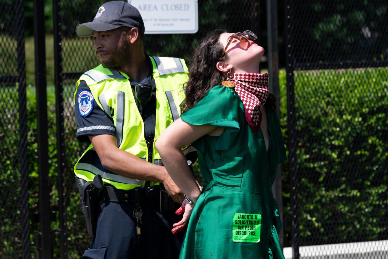 An abortion-rights activist is detained after throwing red paint on the sidewalk outside the Supreme Court in Washington, Saturday, June 25, 2022. The Supreme Court has ended constitutional protections for abortion that had been in place for nearly 50 years, a decision by its conservative majority to overturn the court's landmark abortion cases.