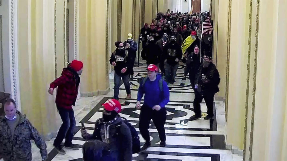 In this image taken from video footage released in a criminal complaint by the U.S. District Court for the District of Columbia, Alexander Sheppard, center, joins other rioters who stormed the U.S. Capitol on Jan. 6, 2021, in Washington. Sheppard, of Ohio, was arrested Tuesday, Feb. 23, in connection with the deadly insurrection after being identified by an acquaintance to the FBI, according to U.S. District Court documents. (U.S. District Court for the District of Columbia via AP)