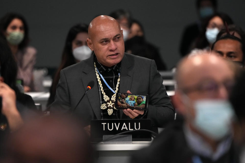 Seve Paeniu, a Tuvaluan politician shows photos of his grandchildren on his phone during a stocktaking plenary session at the COP26 U.N. Climate Summit in Glasgow, Scotland, Saturday, Nov. 13, 2021. Going into overtime, negotiators at U.N. climate talks in Glasgow are still trying to find common ground on phasing out coal, when nations need to update their emission-cutting pledges and, especially, on money. (AP Photo/Alastair Grant)