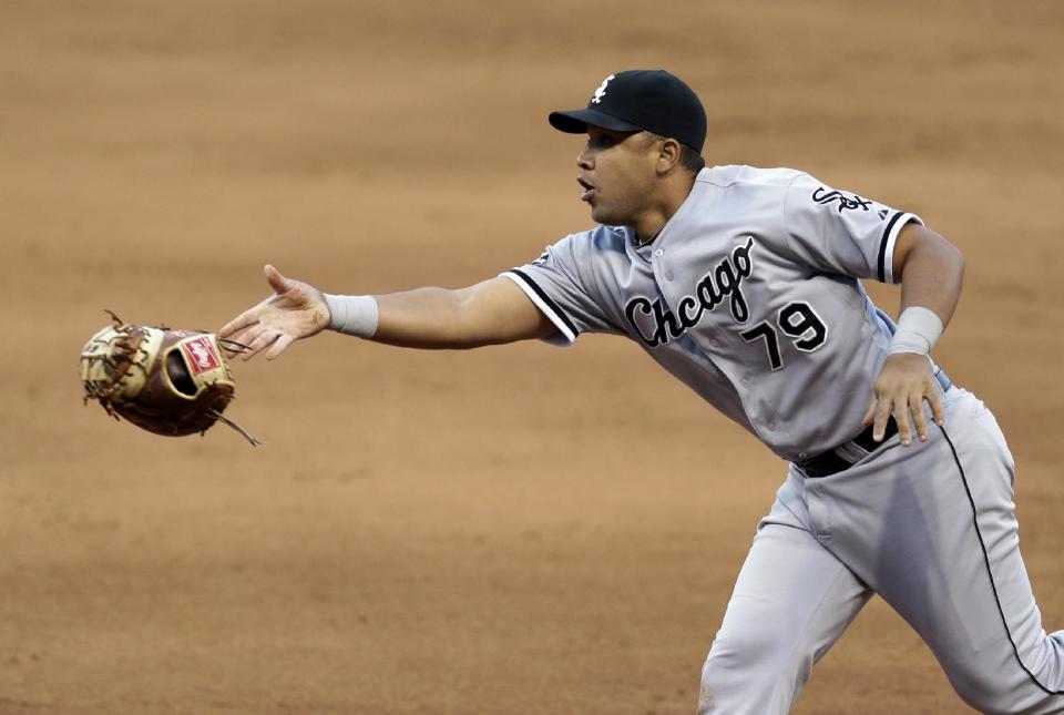 Chicago White Sox's Jose Abreu tosses his glove with the ball to starting pitcher Scott Carroll to get Cleveland Indians' Lonnie Chisenhall out at first base in the sixth inning of a baseball game, Saturday, May 3, 2014, in Cleveland. Chisenhall was out. (AP Photo/Tony Dejak)