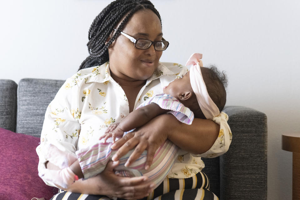 Asian Davis, 33, of Sikeston, Mo., cradles her 8-month-old daughter, Mira White during an interview on Oct. 3, 2023, in St. Louis. Davis and her lawyers say Mira suffered brain damage in March after developing bacterial meningitis tied to powdered infant formula contaminated with Cronobacter sakazakii, a germ known to cause severe disease in young babies. (AP Photo/Michael Thomas)