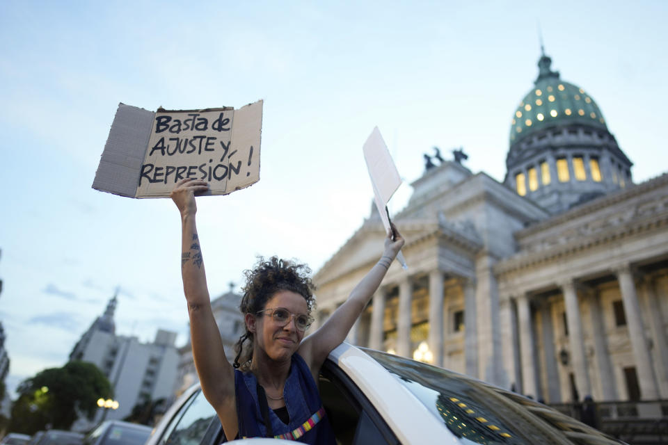 Una mujer se asoma por la ventana de un vehículo sosteniendo carteles de rechazo a la reforma económica promovida por el presidente argentino, Javier Milei, a su paso por el Congreso en Buenos Aires, Argentina, el martes 6 de febrero de 2024. La Cámara de Diputados tiene en debate el proyecto de ley que incluye una variedad de medidas económicas, administrativas, penales y medioambientales. (AP Foto/Natacha Pisarenko)