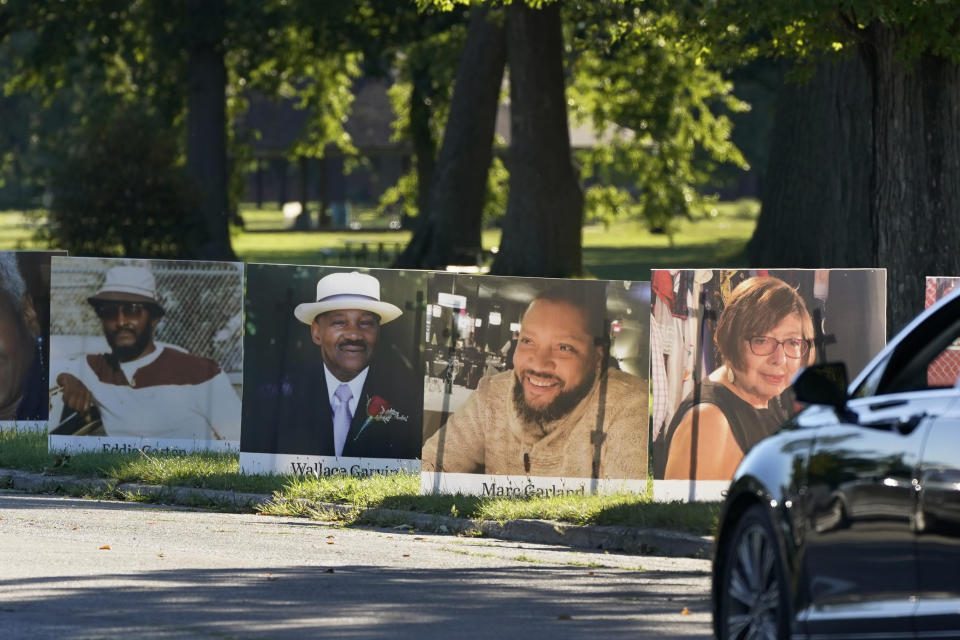 A procession of vehicles drive past photos of Detroit victims of COVID-19, Monday, Aug. 31, 2020 on Belle Isle in Detroit. Families have a chance to take one last public look at their lost loved ones in the nation's first citywide memorial to honor victims of the pandemic. Mourners will join 14 consecutive funeral processions to drive past nearly 900 large poster-sized photos of their loved ones staked around the island. (AP Photo/Carlos Osorio)