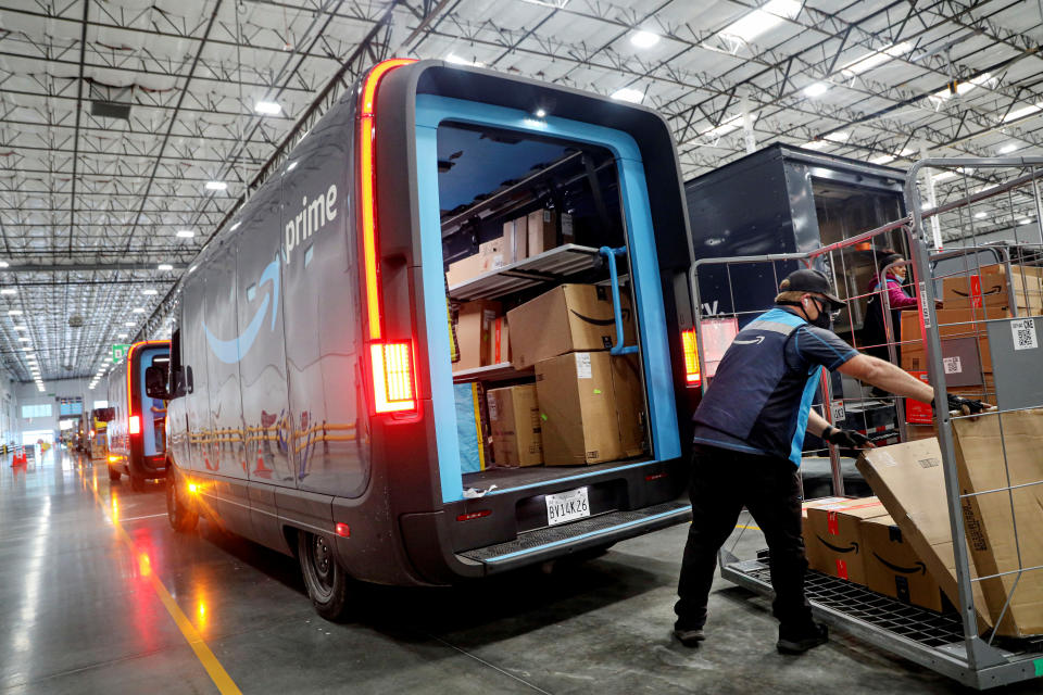 I lavoratori caricano i pacchi nei camion Amazon Rivian Electric presso una struttura Amazon a Poway, California, USA 16 novembre 2022. REUTERS/Sandy Huffaker