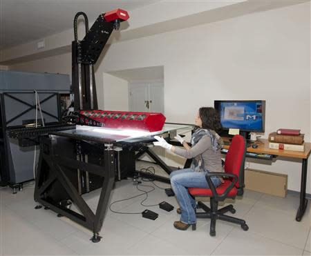 A woman is seen as she works with a scanner in the Vatican Library at the Vatican in this March 20, 2014 handout released by Biblioteca Apostolica Vaticana (Vatican Apostolic Library). REUTERS/Biblioteca Apostolica Vaticana/Handout via Reuters