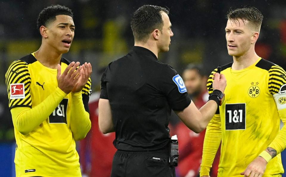 Jude Bellingham and Dortmund team-mate Marco Reus discuss with referee Felix Zwayer during a match with Bayern Munich on December 3, 2021.