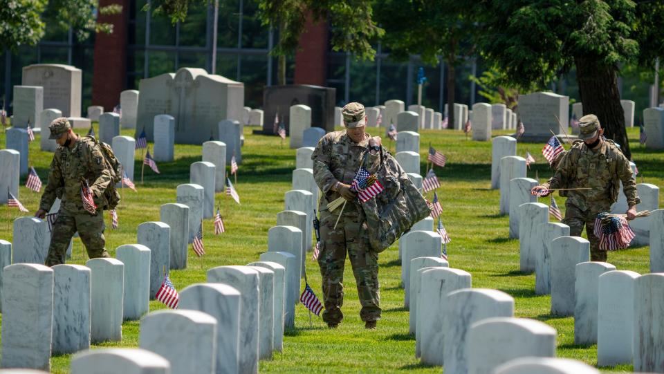 Members of the 3rd United States Infantry Regiment, also known as The Old Guard, place flags in front of each headstone as part of the "Flags In" ceremony at Arlington National Cemetery in Arlington, Va. on Thursday, May 27, 2021. Since 1948, The Old Guard has placed flags at each headstone in honor of Memorial Day.