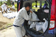 A city official loads sandbags into the car of an applicant in Iwaki, Fukushima prefecture, Monday, July 26, 2021 in preparation for a tropical storm heading toward northeastern Japan. Storm and high wave warnings were issued for Miyagi and Fukushima prefectures. (Kyodo News via AP)