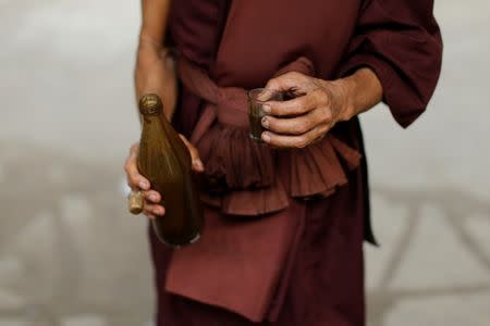 A Buddhist monk holds a glass with a vomit-inducing medication, before giving it to a rehabilitation patient at the detox area at Wat Thamkrabok monastery in Saraburi province, Thailand, February 3, 2017. REUTERS/Jorge Silva