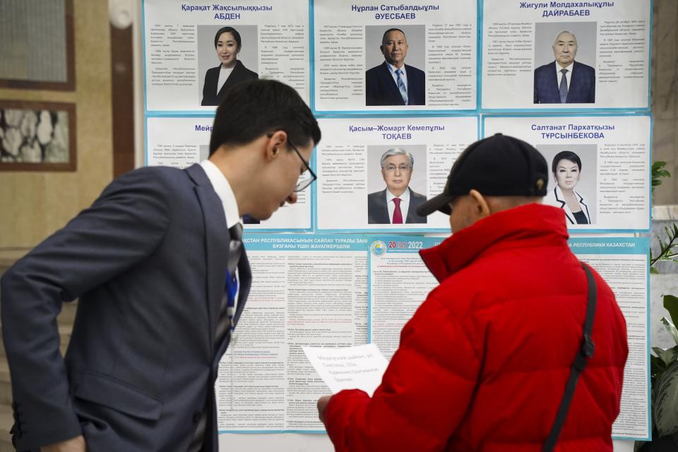 A member of the election commission, left, speaks to a voter in front of an election poster with biographies of presidential candidates at a polling station in Almaty, Kazakhstan, Sunday, Nov. 20, 2022. Kazakhstan's president appears certain to win a new term against little-known challengers in a snap election on Sunday. Five candidates are on the ballot against President Kassym-Jomart Tokayev, who faced a bloody outburst of unrest early this year and then moved to marginalize some of the Central Asian country's longtime powerful figures. (Vladimir Tretyakov/NUR.KZ via AP)