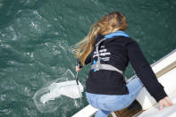 Marine biologist Catarina Pereira catches plastic floating on the Tagus River during a boat trip to watch dolphins at the mouth of the Tagus river in Lisbon, Friday, June 24, 2022. Starting Monday the United Nations is holding its five-day Oceans Conference in Lisbon hoping to bring fresh momentum for efforts to find an international agreement on protecting the world's oceans. (AP Photo/Armando Franca)