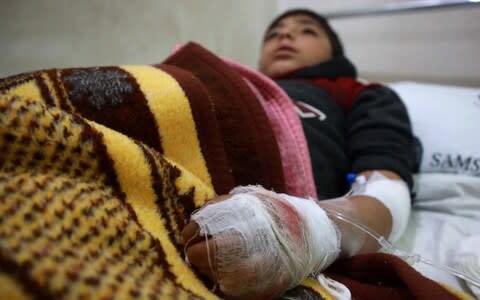 An injured boy rests after receiving treatment at Aqrabat hospital following pro-Syrian regime bombardment - Credit: AFP