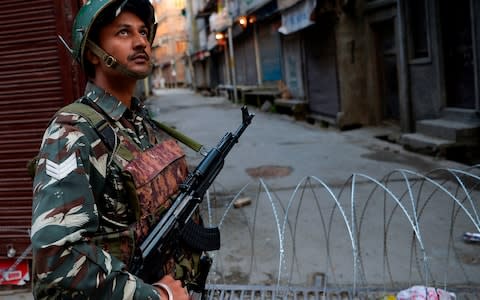 A security guard stands on a street in downtown Srinagar amid a communications blackout - Credit: SAJJAD HUSSAIN/AFP