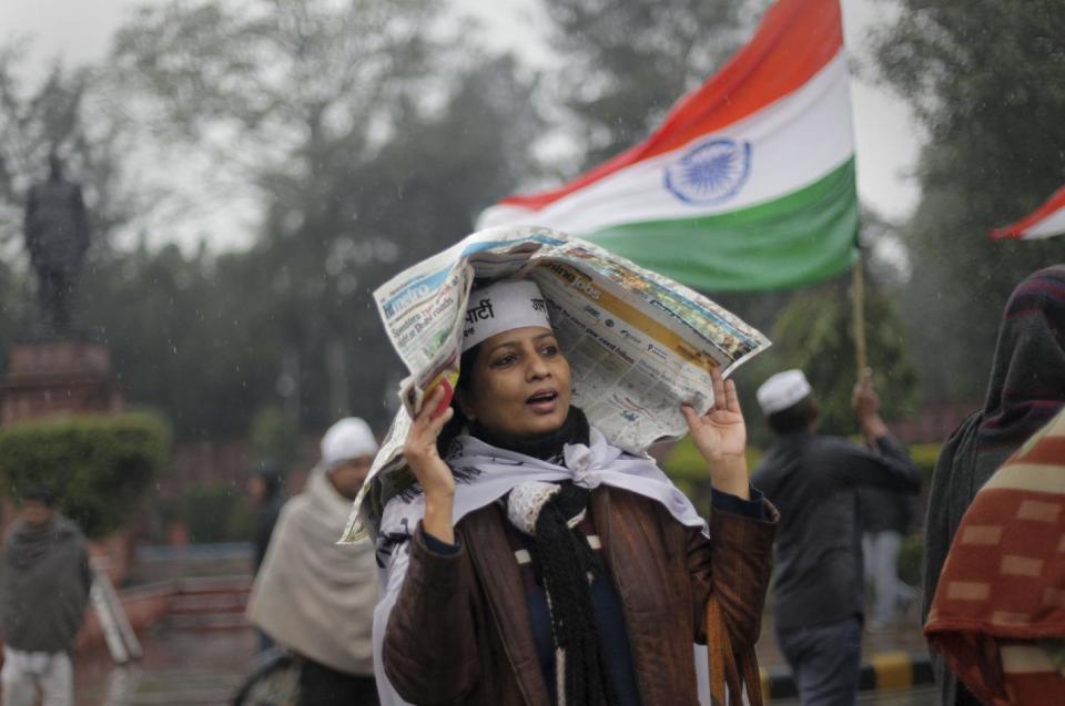 A supporter of New Delhi Chief Minister Arvind Kejriwal uses a newspaper to protect herself from the rain during a demonstration against the police in New Delhi, India, Tuesday, Jan. 21, 2014. The fiery leader of India's capital has accused the police force of targeting the poor for petty offenses and refusing to combat serious crime. (AP Photo/Tsering Topgyal)