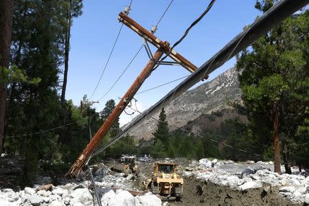 A broken power pole is pictured on a road damaged by a mudflow triggered by flash floods in the San Bernardino National Forest community of Forest Falls, California August 4, 2014. REUTERS/Jonathan Alcorn