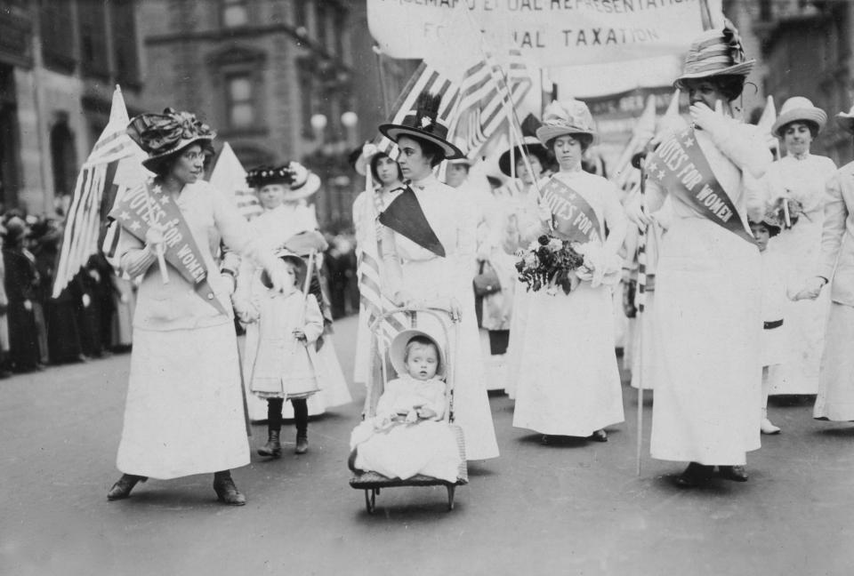 Why Did Suffragettes Wear White?, View of women participating in a suffragette parade in New York City, 1912. They wave flags, wear 