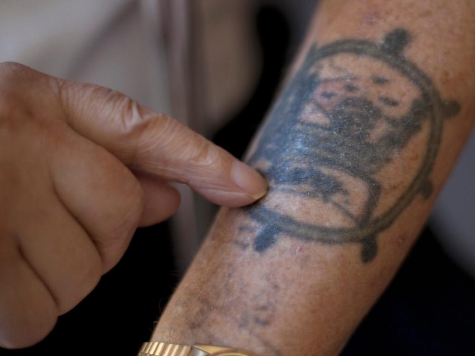 Veteran Jack Stapleton, a fireman during the Second World War points to one of many tattoos on his arm